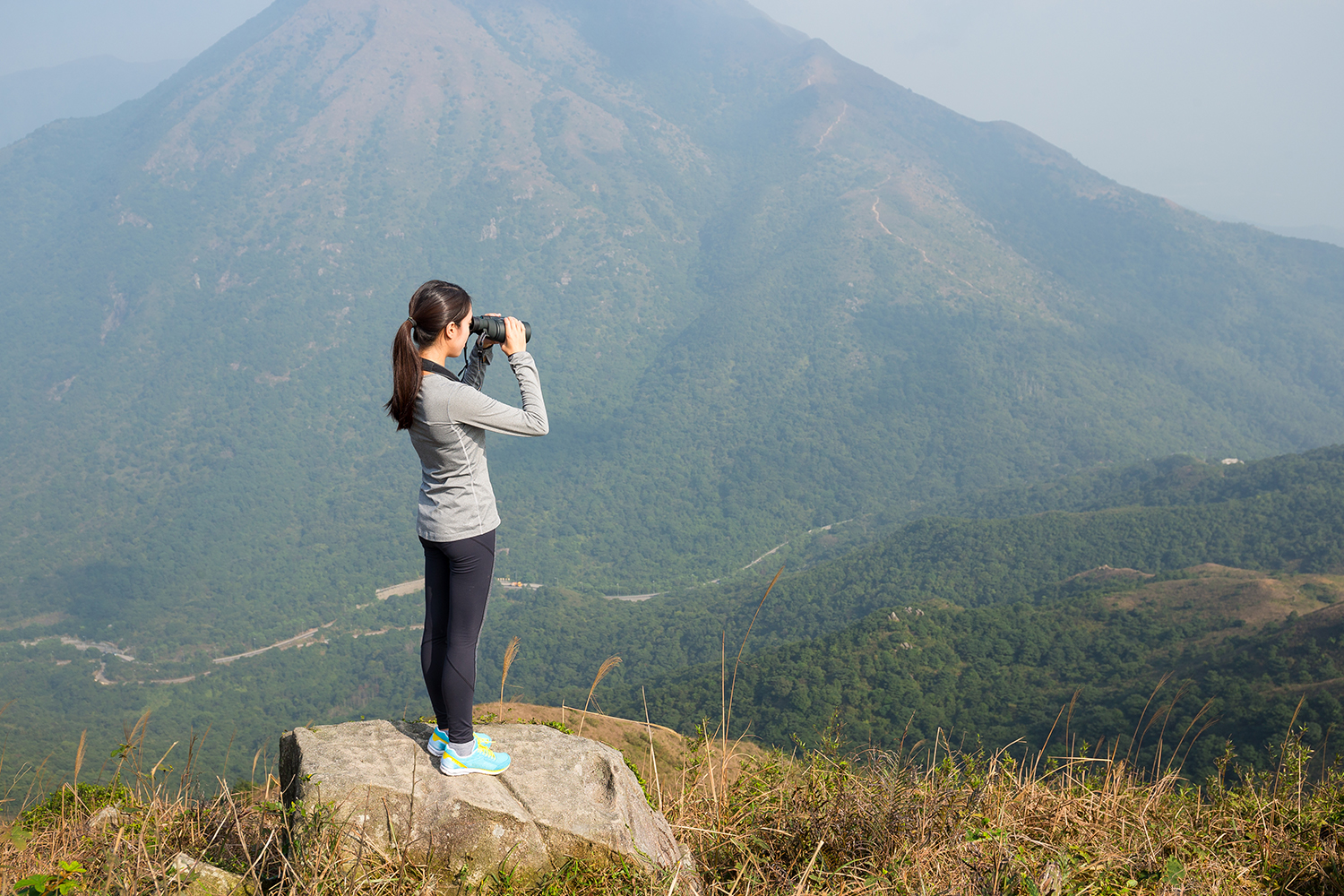 Woman looking though binoculars at mountain